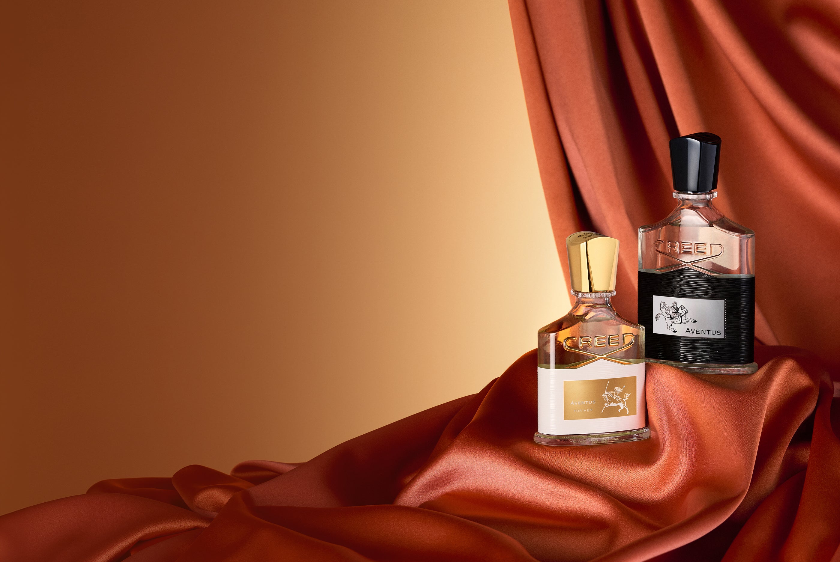 Aventus and Aventus For Her with orange curtain and yellow background.